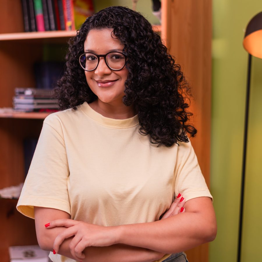 Dálete Cavalcante sorrindo, de braços cruzados.